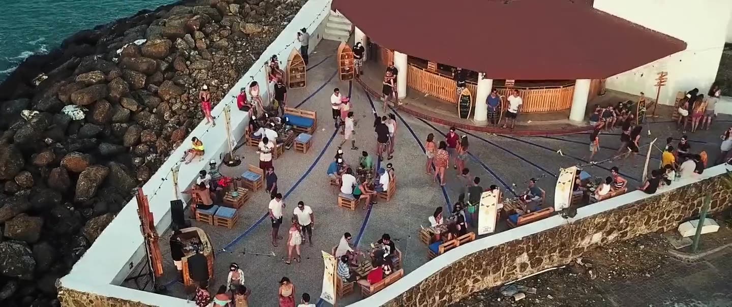 Vista aérea de una terraza junto al mar llena de gente al atardecer